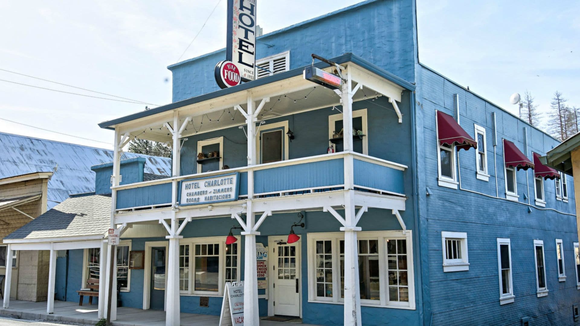 Blue two-story hotel with red awnings and a sign reading "Hotel Charlotte."